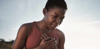 A woman in athletic wear holding her chest with a pained expression outdoors
