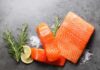 Fresh salmon fillets with lemon and herbs on a dark surface