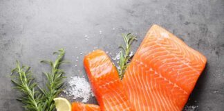 Fresh salmon fillets with lemon and herbs on a dark surface