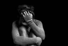 Stanford Scientists Crack Depression—Results Will Shock America A person sitting in a curled position, covering their face with one hand in a dark setting