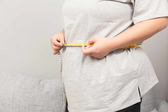 shutterstock_2025052427.jpg Person measuring their waist with a tape measure