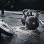 Dumbbell Row: Avoid This Spine-Breaking Error Kettlebells and weights on a gym floor with chalk dust