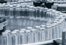 Close-up of glass vials arranged in a circular conveyor system in a pharmaceutical setting