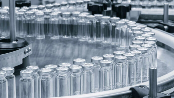 Close-up of glass vials arranged in a circular conveyor system in a pharmaceutical setting