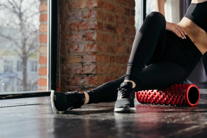 Person using a foam roller for stretching in a fitness studio