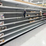 Empty grocery store shelves with a few snack items remaining