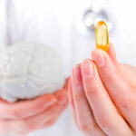 Billion-Dollar Brain Pills: Miracle or Scam? A medical professional holding a brain model in one hand and a yellow supplement capsule in the other
