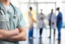 Physician Burnout Crisis: The Shocking Toll A healthcare professional in scrubs with a stethoscope, standing with arms crossed in a hospital setting