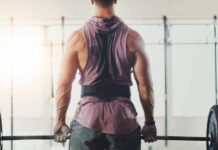A muscular person preparing to lift a barbell in a gym setting