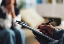 A therapist taking notes during a session with a client in the background