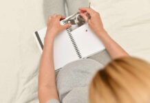 Pregnant woman writing in a journal while holding an ultrasound photo