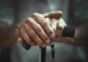 Two-Stage Aging Discovery Shocks Scientists Close-up of elderly hands resting on a walking cane