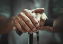 Two-Stage Aging Discovery Shocks Scientists Close-up of elderly hands resting on a walking cane