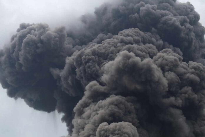 Thick dark smoke billowing into the sky