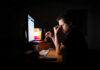 Night Shift’s Hidden Health Dangers A man sitting at a desk with a computer, holding glasses and looking stressed