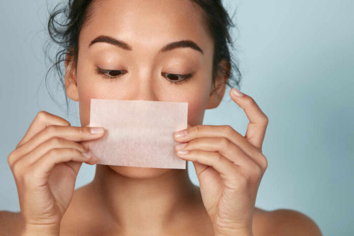 Skin,Care.,Woman,Holding,Facial,Oil,Blotting,Paper,Portrait.,Closeup Woman holding a skincare strip in front of her face