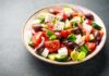 Low-Protein Diet Sparks Lifespan Debate A vibrant salad with tomatoes, cucumbers, olives, and feta cheese