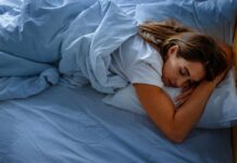 A woman sleeping peacefully on a bed with blue sheets