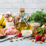 Olive Oil Cancer Twist Stuns Researchers A variety of fresh foods including fruits, vegetables, and oils arranged on a table