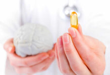 Latest Drug To Slow Development of Alzheimer’s A medical professional holding a brain model in one hand and a yellow supplement capsule in the other