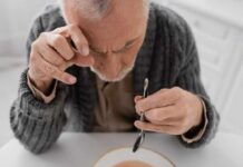 Aging Nerves Rebooted By Simple Fix Elderly man focusing intently on a spoon while preparing to eat