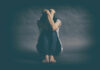 Why Depression is More Prevalent in Women A person sitting on the floor with their arms wrapped around their knees, conveying a sense of distress