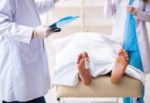 Household Chore with a Fatal Cost Medical staff stand near a covered body on a gurney with a toe tag