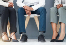Could Your Shoes Be Ruining Your Feet and Posture? Three individuals in business attire sitting on chairs, showcasing their shoes and legs