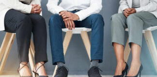Three individuals in business attire sitting on chairs, showcasing their shoes and legs