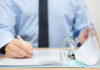 Employment and Working as a Person With Dementia A person in a blue shirt writing on a document while holding a binder