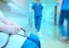 A healthcare professional holding a stethoscope in a hospital corridor