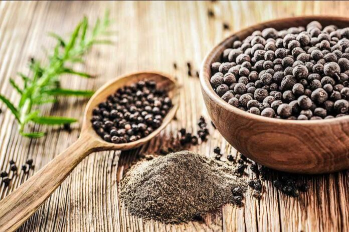 shutterstock_1013574415 Black peppercorns in a wooden bowl and spoon with ground pepper