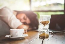 Terrifying ‘Sleeping Beauty’ Syndrome Explained Hourglass on table with coffee cup and sleeping person in background