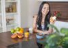 Woman sitting at kitchen counter holding a supplement bottle