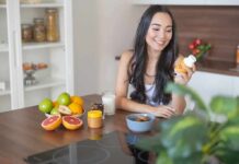 Woman sitting at kitchen counter holding a supplement bottle