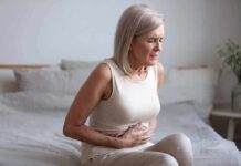 Calcium Intake and Bowel Cancer Risk Woman sitting on bed holding her stomach in pain