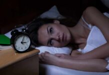 Night Pee Fix? This Vitamin Could End Nighttime Bathroom Trips Woman lying awake in bed beside an alarm clock