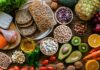 A variety of fresh foods including vegetables, fruits, grains, and proteins arranged on a wooden surface