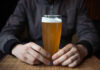 Cancer Warning: Feds Nuke ‘Safe’ Drinking Person holding a glass of craft beer in a bar
