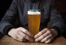 Cancer Warning: Feds Nuke ‘Safe’ Drinking Person holding a glass of craft beer in a bar