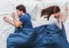 Couple sleeping back to back in bed under blue blanket