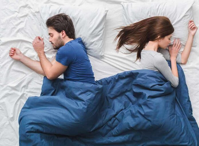 shutterstock_1036490839 Couple sleeping back to back in bed under blue blanket