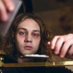 Why The Wrong Zip Code Derails Addiction Recovery young person leaning over a table with hands arranging items