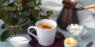 Cup of coffee with milk, butter, and spices on a table