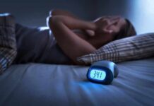 Wake-Up Trick Outsmarts Insomnia Person lying awake in bed beside a glowing digital alarm clock