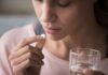 The Common Painkiller That TRIGGERS Hallucinations Woman holding a white pill and a glass of water