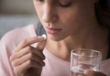 The Common Painkiller That TRIGGERS Hallucinations Woman holding a white pill and a glass of water