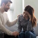 Man comforting a distressed woman on a couch