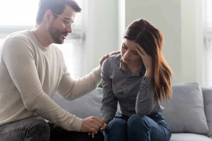 Man comforting a distressed woman on a couch