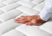 Sleep Essential Checklist for Better Nights Hand pressing a quilted white mattress surface